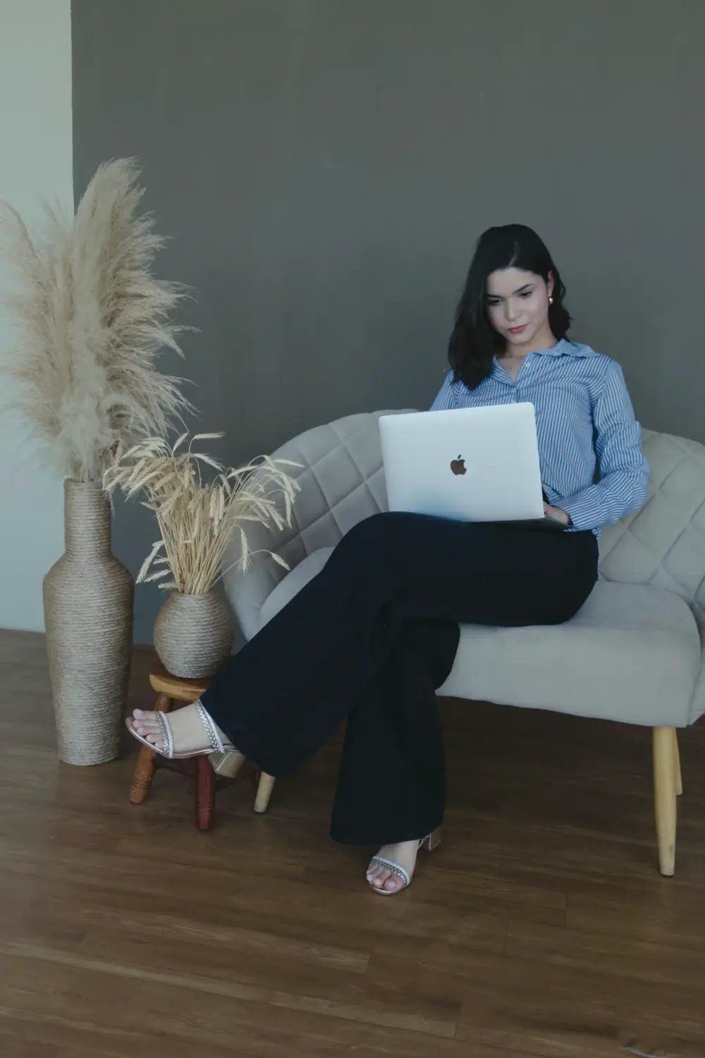 Pâmella sentada numa poltrona, trabalhando no notebook.