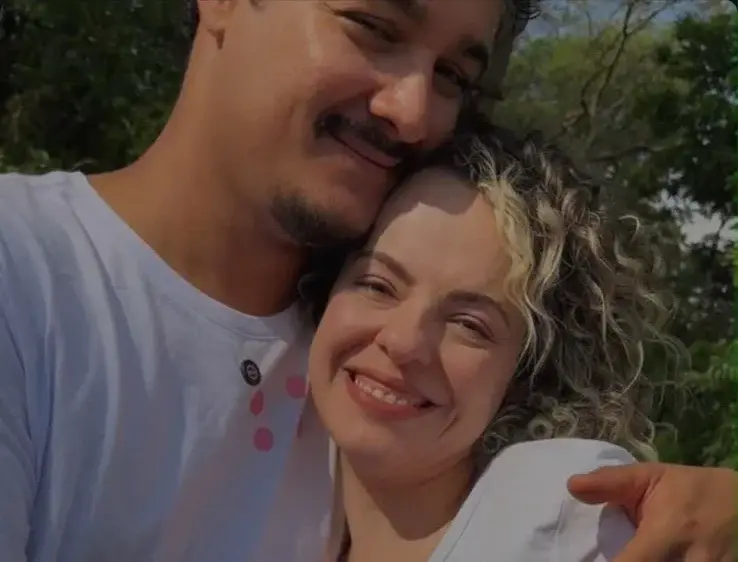 Casal abraçado, sorrindo, ao ar livre.